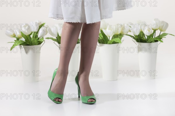 Woman's legs and white flowers on an isolated studio background