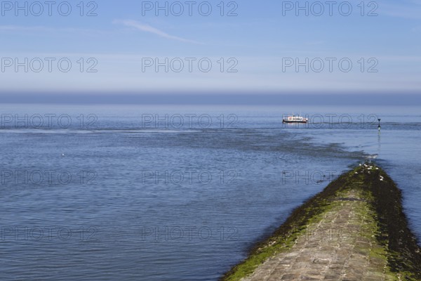 The photo shows a jetty with a survey vessel by day on the island of Baltrum
