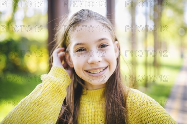 Beautiful and happy teenage girl with braces smiling to camera in yellow clothes in park. Concept of dentist and orthodontist. Pretty teenage girl wearing teeth appliance smiling cheerfully outdoors