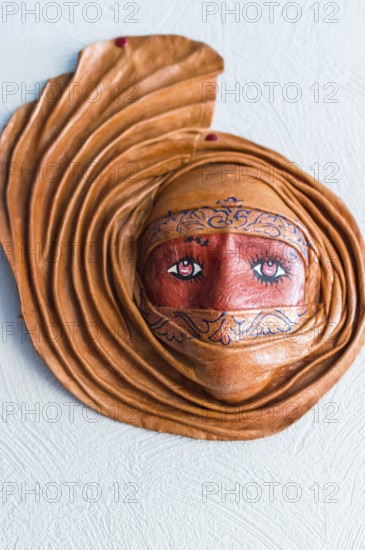 Fashioned from clay mask hanging on a white wall