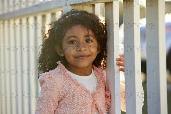 Happy toddler kid girl portrait in a park fence latin ethnicity