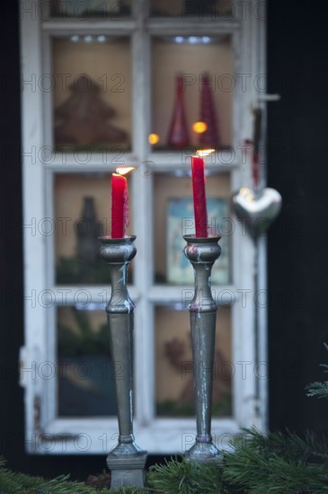 Two red candles in front of a decorated window and Christmas decorations, borken, münsterland, germany