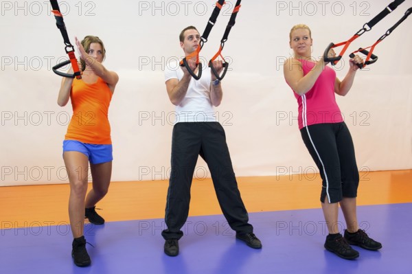 Young woman doing suspension training at the health club