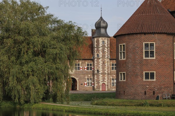 Historic ensemble of buildings with round tower and moat, surrounded by greenery, Raesfeld, Münsterland, Germany, Europe