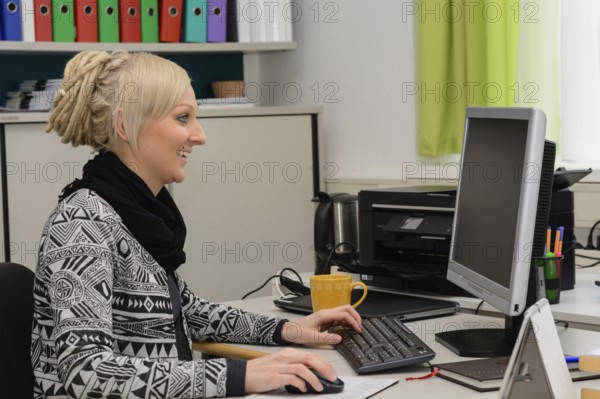 Friendly executive secretary works at the computer workstation