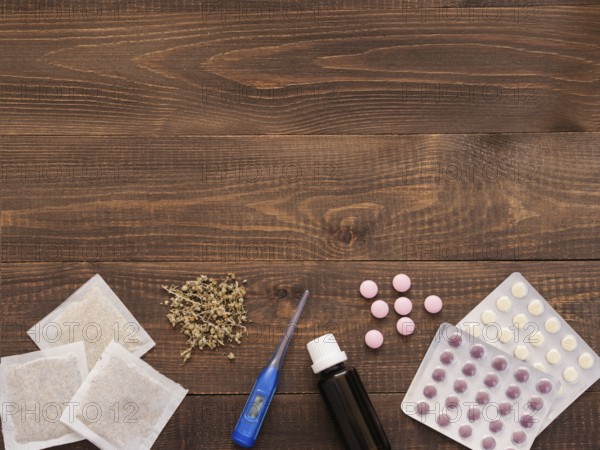 Tablets, drops, herbals and thermometer on a dark wooden background with copy space. Herbal medicine VS Chemical medicine the alternative healthy care. Flat lay or top view