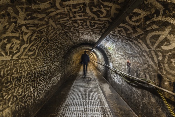 Anderlecht, Brussels, Belgium, 07 16 2019- Man walking in the industrial interiors of the sewer museum showing the main tunnel of the Chaussee de Mons drain, Europe