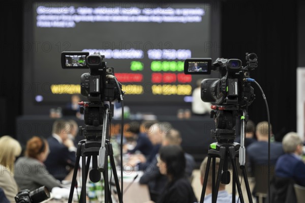 Camera during shareholders' meeting with big screen in the background