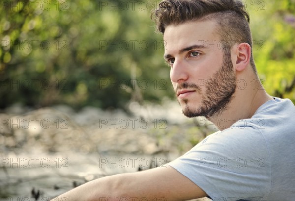 Portrait of handsome young man in white t-shirt outdoors, looking to a side