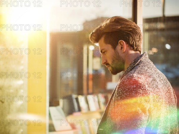 Handsome Young Man in Black Elegant Suit Looking at Displayed Fashion Items in Glass Window Boutique at the High Street Side