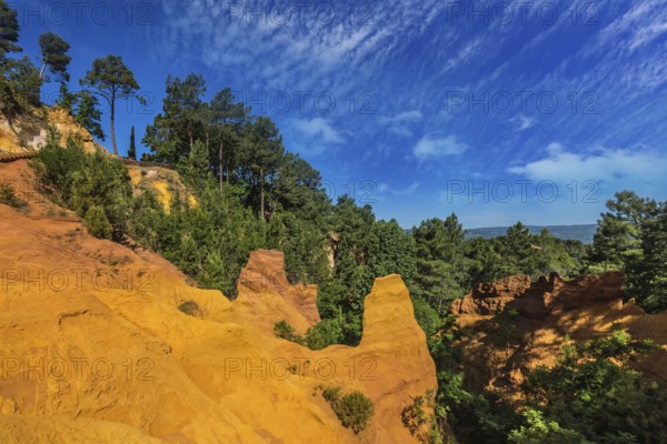 Multi-colored ocher outcrops - from yellow to orange-red. Green trees create a beautiful contrast with the ocher. Roussillon, Provence Red Village