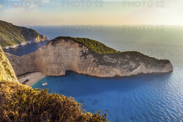 The magical island of Zakynthos on the Mediterranean. The cove with a small sandy beach. The sky glows a warm sunset. Summer holidays in Greece. The concept of a summer beach holiday and photo tourism