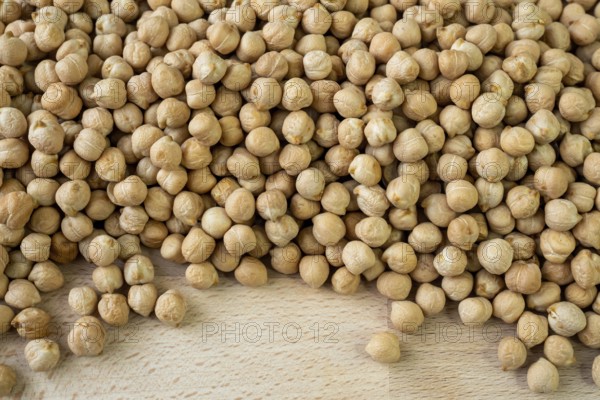 Lot of whole fresh tan chickpea on wooden cutting board. Legumes
