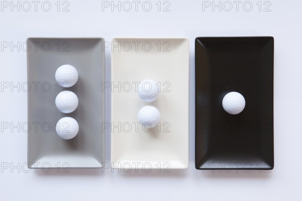 Different ceramic dishes with golf balls on over white background, rectangle dish