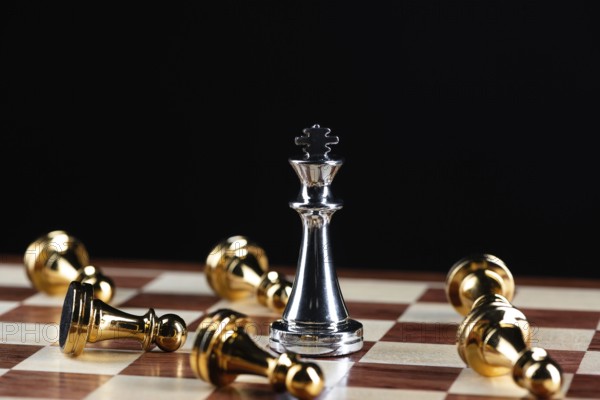 Silver king chess defeats gold pawns on wooden chessboard. Intellectual duel and tactical battle in business. Strategy planning, leadership and teamwork. Checkmate and winning in game concept