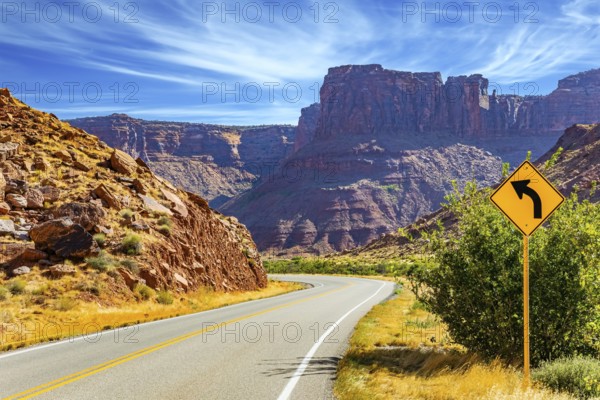 Wide asphalt highway among picturesque hills and rocks of bizarre shapes. The grandiose landscapes of America. Utah Red Sandstones. Fine autumn day