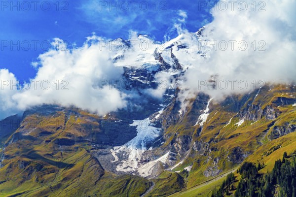Snowy mountain peaks covered with clouds. Flowering alpine meadows and mountains of the Hohe Tauern National Park. The famous mountain road Grossglognerstrasse