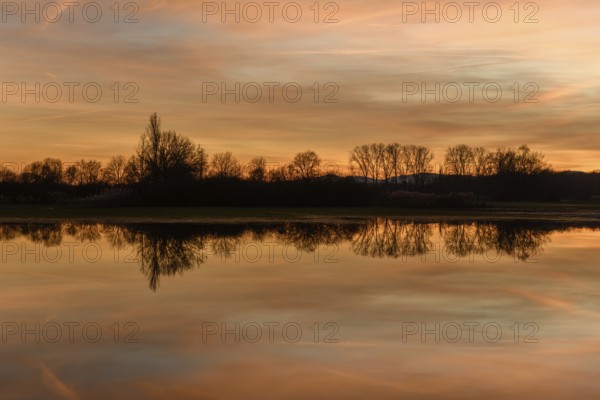 Trees reflecting in the water at sunset. Winter landscape red and orange sky. Bas-Rhin, Alsace, Grand Est, France, Europe