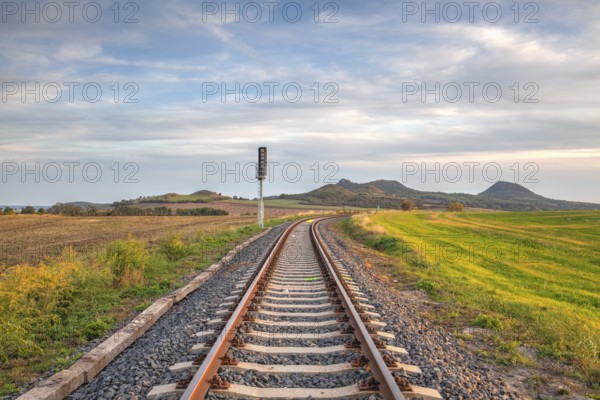 Old Railway tracks running through a field stretch to rural countryside at sunset. Single railway track at sunset, Czech Republic, Europe