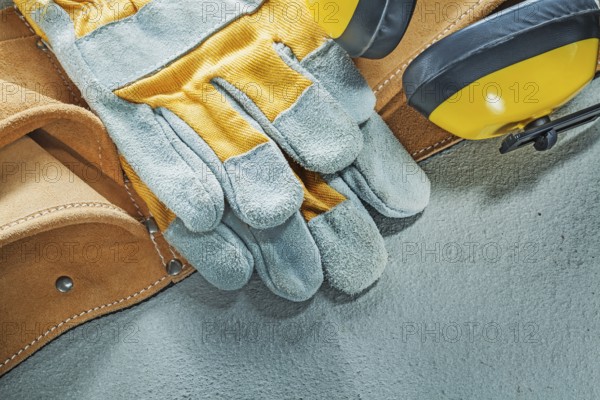 Set of leather tool belt protective gloves earmuffs on concrete background