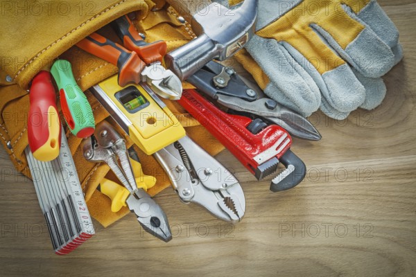 Tools in leather building belt on wooden board top view