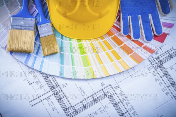 Building helmet protective glove paint brushes and color sampler on blueprint construction concept