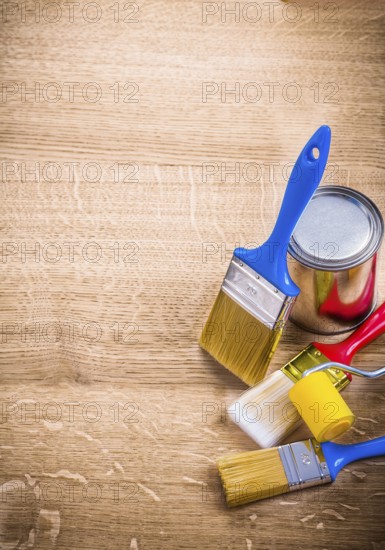 Organized copyspace three paint brushes roller can on wooden board construction concept