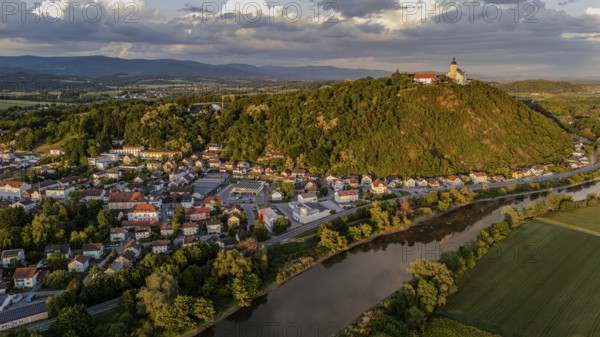 View of a town with a castle on a green hill surrounded by a river in the warm evening light, Bogen, Lower Bavaria