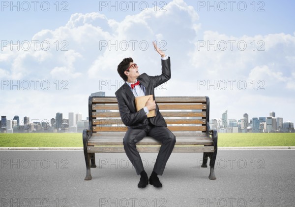 A young student with a book sits on a bench