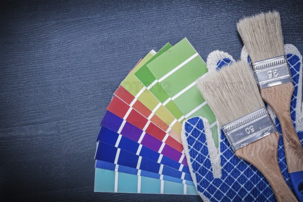 Paintbrushes pantone fan safety gloves on wooden board
