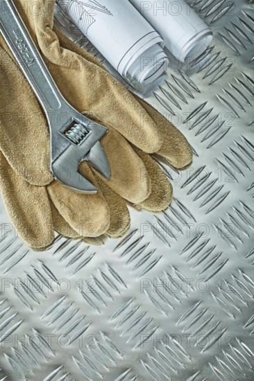 Blueprints adjustable spanner protective gloves on fluted metal sheet