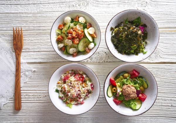 Four salad mix bowls healthy food on white wood table