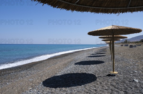 Tropical beach umbrellas providing sunshade for swimmers at an empty beach. Summer vacations. Paphos Cyprus