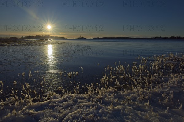 Sunny morning at seashore on a cold winter day with ice on the shoreline, Kallahdenniemi, Helsinki, Finland, Europe