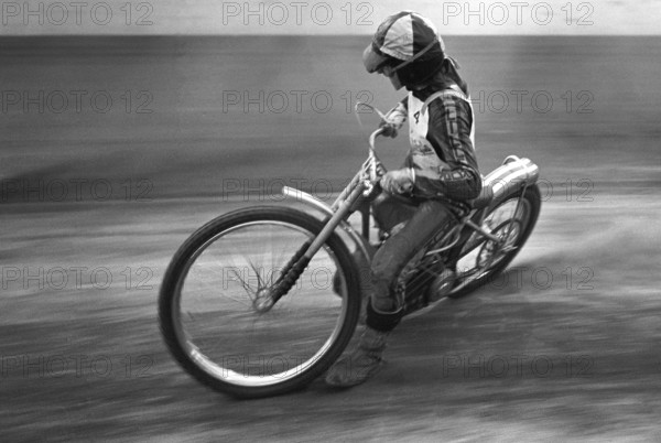 Speedway driver in the 1970s. The speedway motorcycle and driver is pictured racing on the speedway track in a high-speed