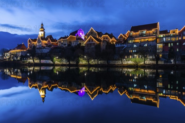 Christmas illuminated house facade of Frohnleiten reflected in the river Mur, blue hour, Frohnleiten, Styria, Austria, Europe