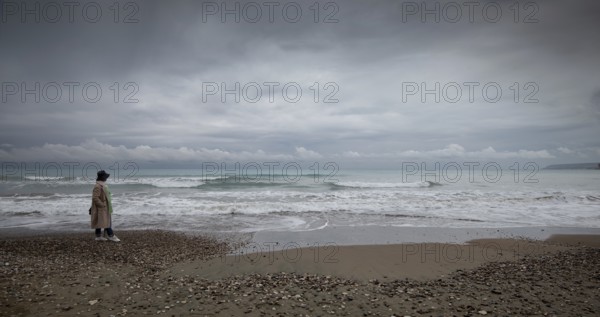 One woman walking on the coast beach. Stormy sky windy waves. Paphos Cyprus