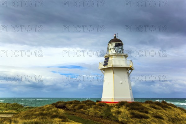 Independent trip to New Zealand. The snow-white lighthouse of Waipapa is visible on the horizon. Scenic South Island on a cloudy windy day. The concept of ecological, active and photo tourism