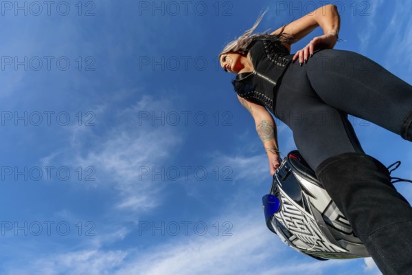 A stunning woman strikes a confident pose beside her high-performance motorcycle. With a fierce gaze and poised stance, she radiates power and passion, embodying the spirit of the open road, Troutman, United States of America