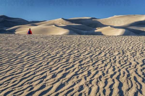 Lost in the sea of sand - a lonely hiker in a dunefield in Great Sand Dunes National Park, Colorado