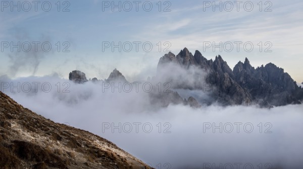 Mountain landscape with fog, at sunset Dolomites at Tre Cime hiking path area in South Tyrol in Italy