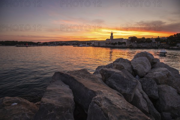 Town on a coast, with a stone fortification a harbour with a view of the sunset. Landscape photo of the town of Krk, Croatia, Europe