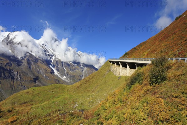 Snow-capped Alps in a beautiful autumn day. The platform supports and fences the highway