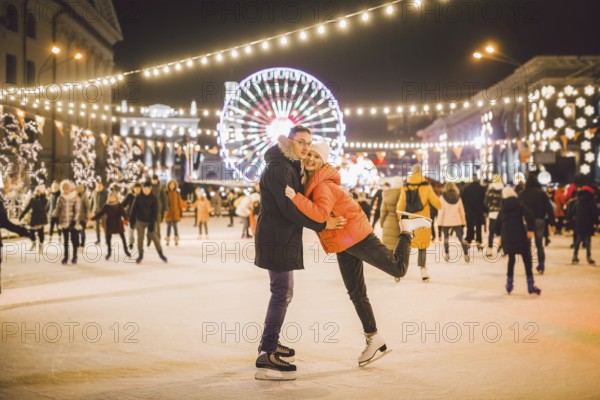Beautiful Couple Ice Skating In City Centre. Young couple skating at a public ice skating rink outdoors. Theme ice skating rink and loving couple. Amazing winter holiday. Saint Valentine's Day