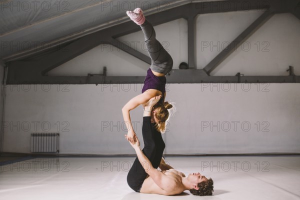 Yogi couple practice. Couple young sporty peoplepracticing acrobatic yoga lesson with partner, man and woman in yogi exercise, arm balance pose, making difficult exercises for body keeping balance
