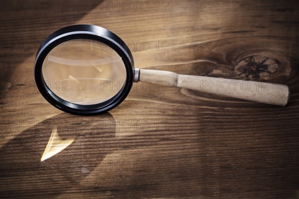 Vintage magnifer glass on old wooden board