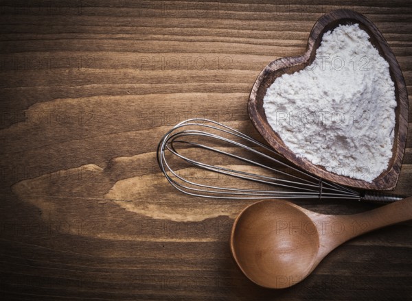 Wooden spoon heartshape bowl flower beater on wood board