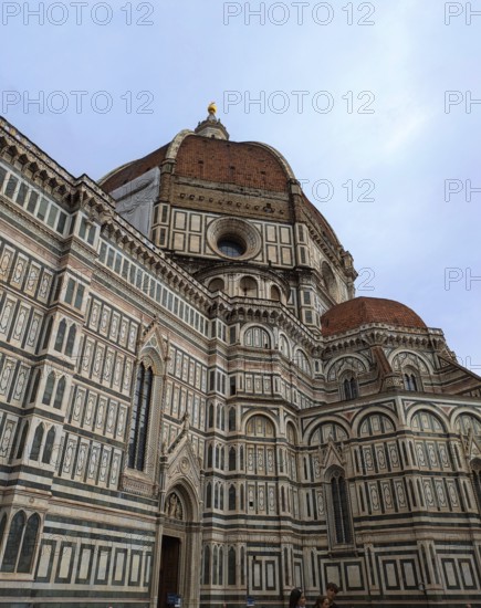 Florence Cathedral with its intricate marble facade and iconic red dome under a cloudy sky. Florence, Italy, Europe