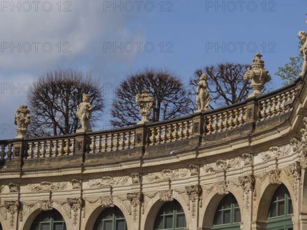 Detailed baroque design of the Zwinger with sculptures and bare trees in front of a blue sky, Dresden, Saxony, Germany, Europe