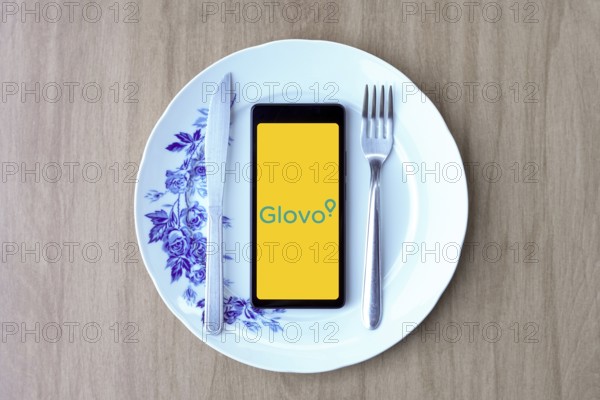 April 29, 2024, Brazil. In this photo illustration, the Glovo logo is displayed on a smartphone screen inside a plate with cutlery